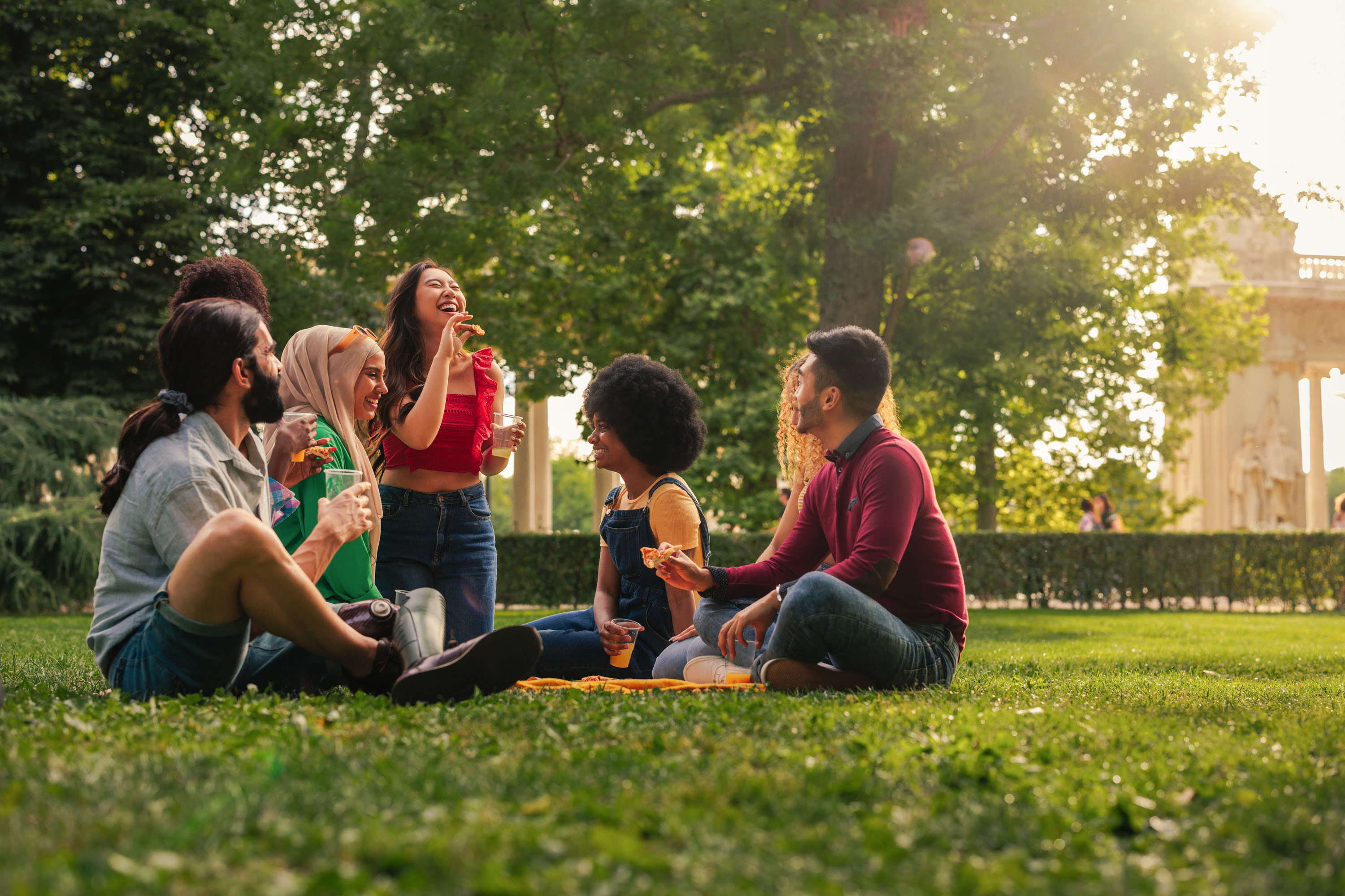 A group of friends enjoying laughing together on a sunny day in a park.